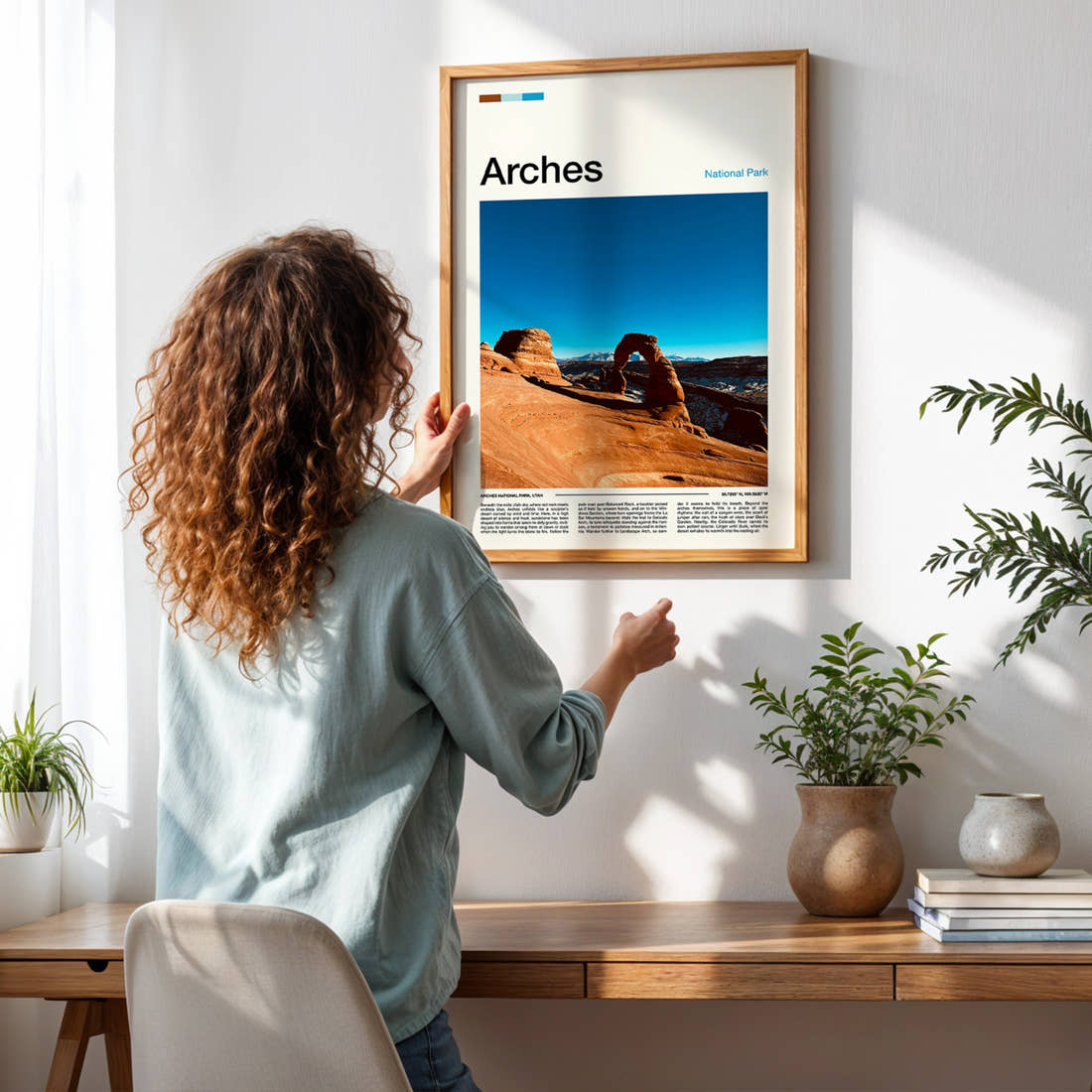 Arches Delicate Arch View Travel Print framed on a pale wall beside houseplants