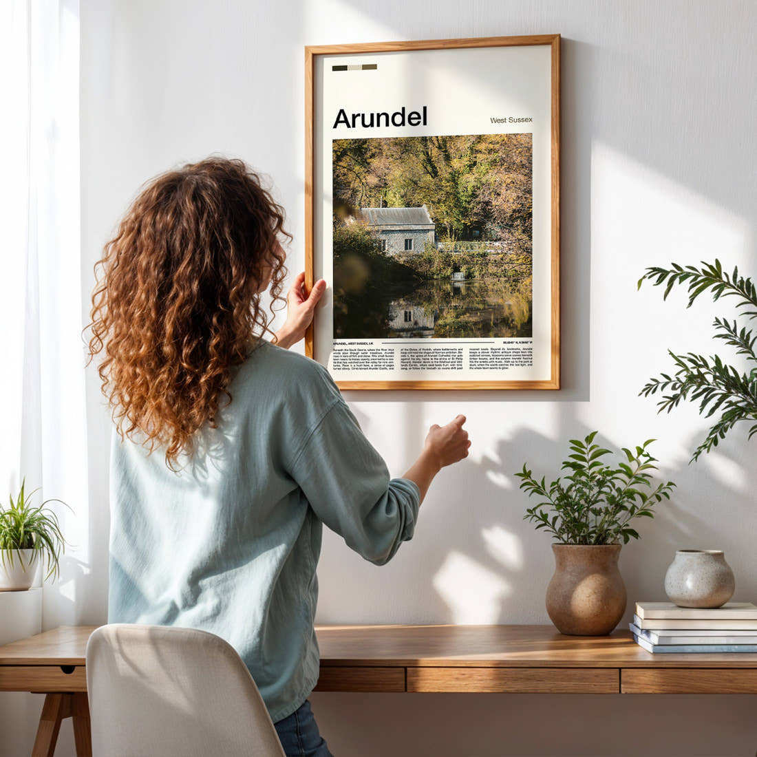 Arundel Riverside Mill Cottage Travel Print framed on a pale wall beside houseplants