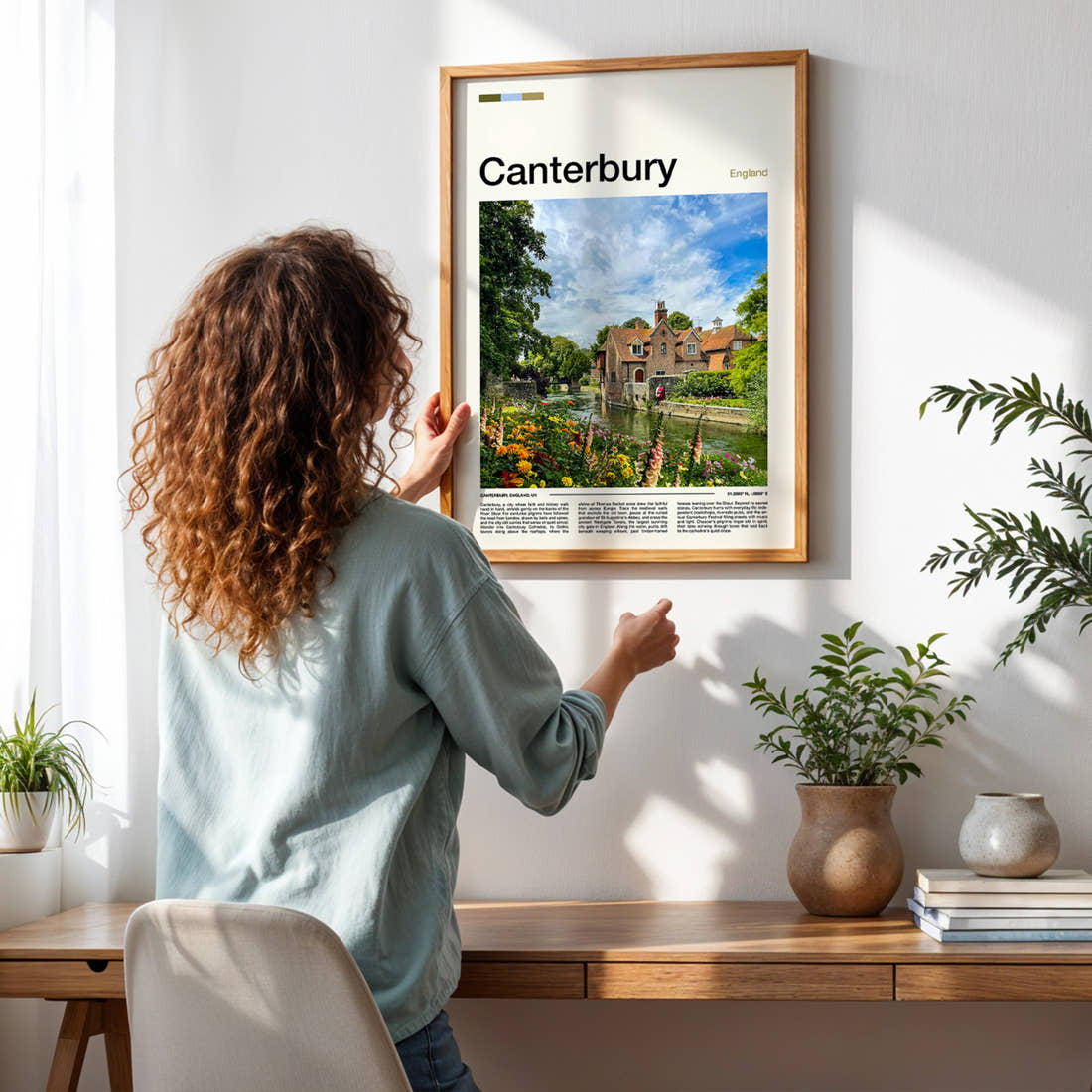 Canterbury Riverside Cottages And Blooms Travel Print framed on a pale wall beside houseplants
