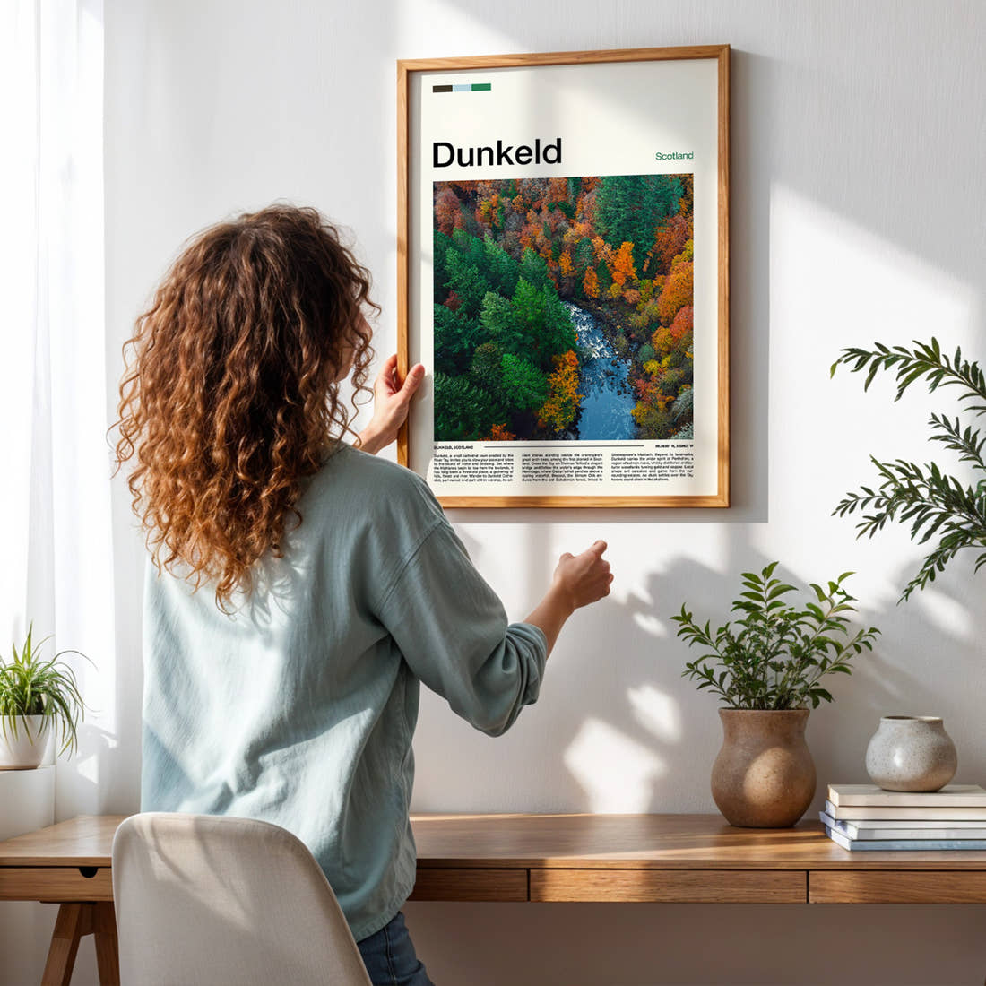 Dunkeld Autumn Forest River Travel Print framed on a pale wall beside houseplants