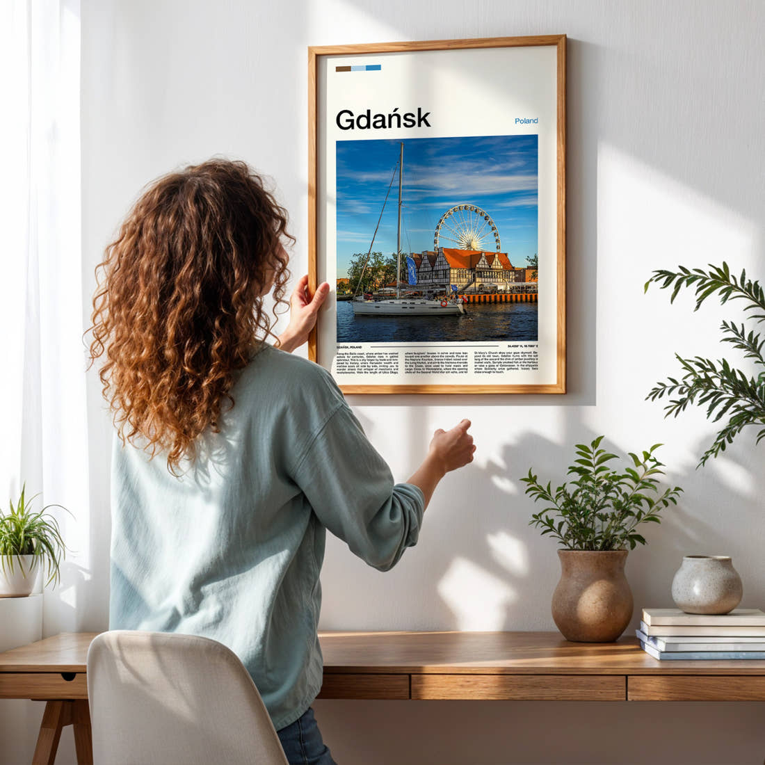 Gdańsk Ferris Wheel Waterfront Travel Print framed on a pale wall beside houseplants