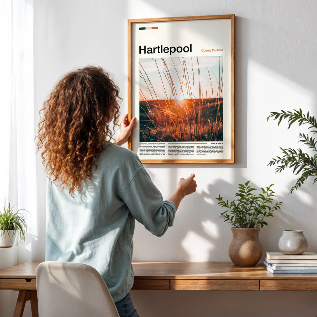 Hartlepool Golden Grass Sunset Travel Print framed on a pale wall beside houseplants