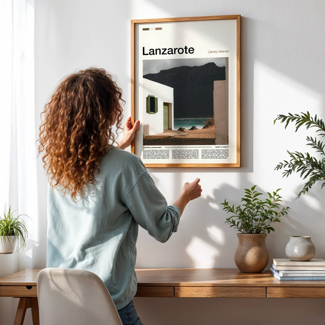 Lanzarote Whitewashed House, Volcanic Cliff Travel Print framed on a pale wall beside houseplants
