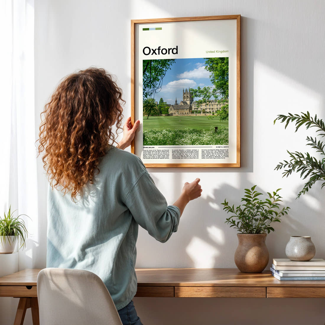 Oxford College Tower And Lawn Travel Print framed on a pale wall beside houseplants
