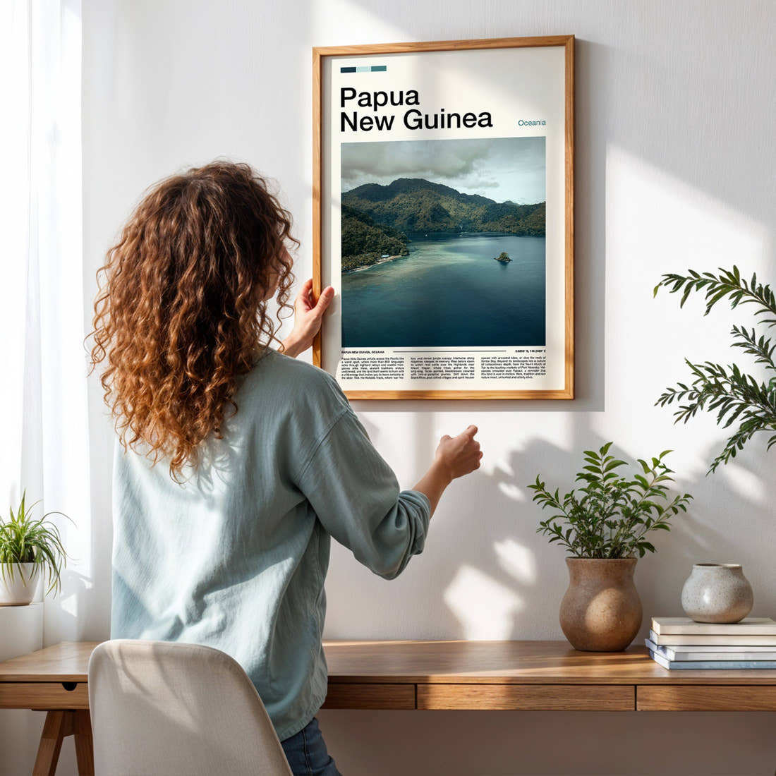 Papua New Guinea Misty Coastal Inlet Travel Print framed on a pale wall beside houseplants