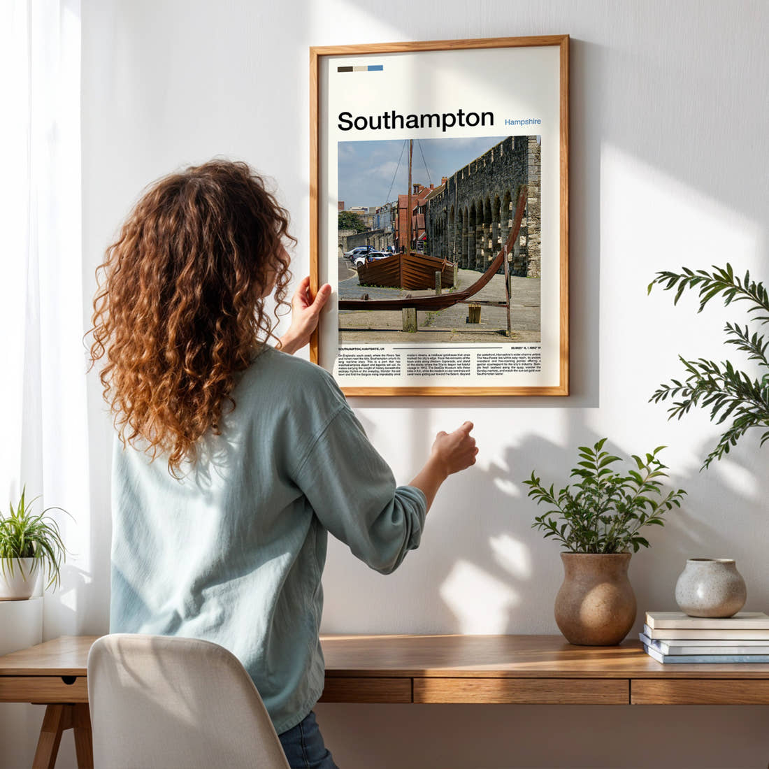 Southampton Medieval Wall And Boat Travel Print framed on a pale wall beside houseplants