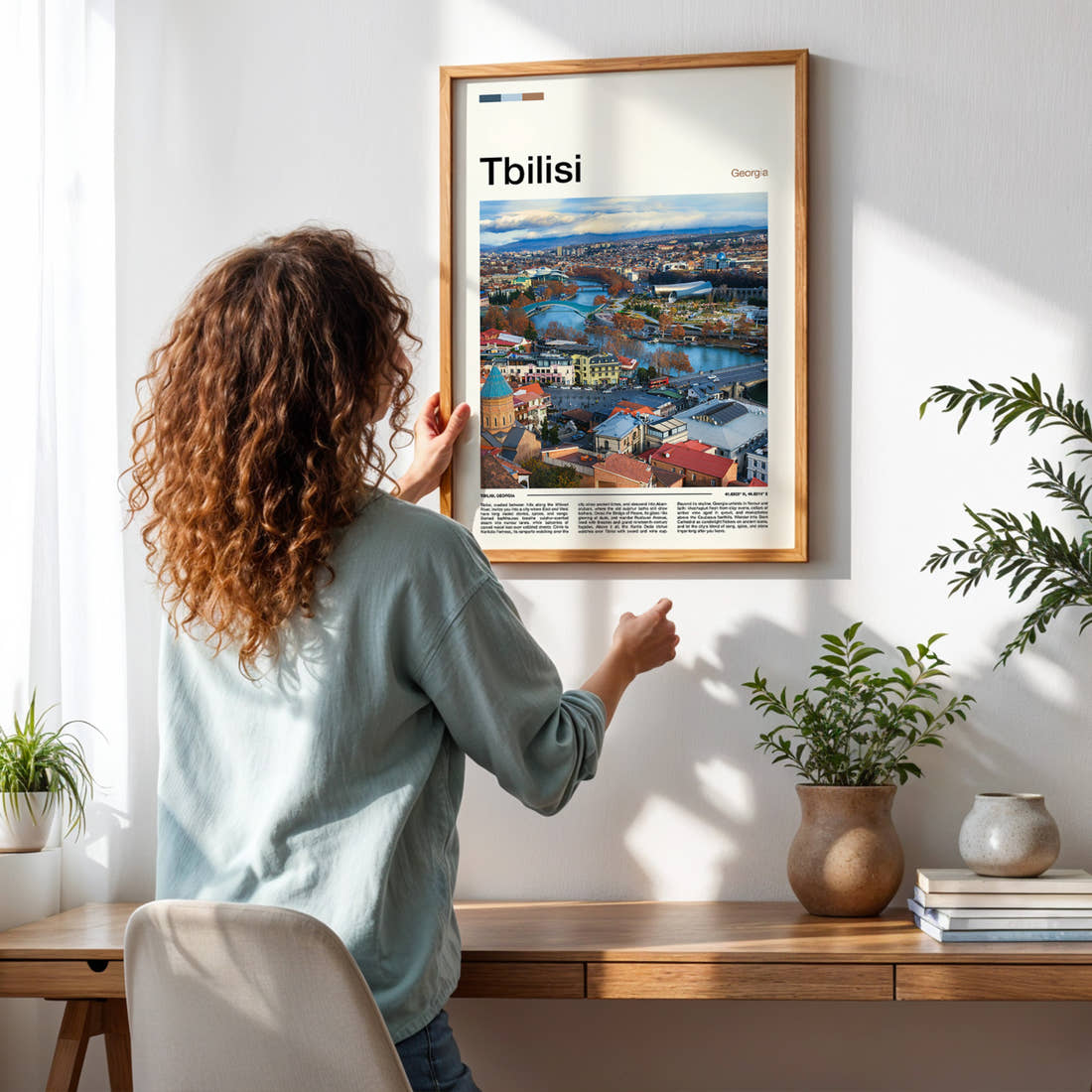 Tbilisi Riverside City View Travel Print framed on a pale wall beside houseplants