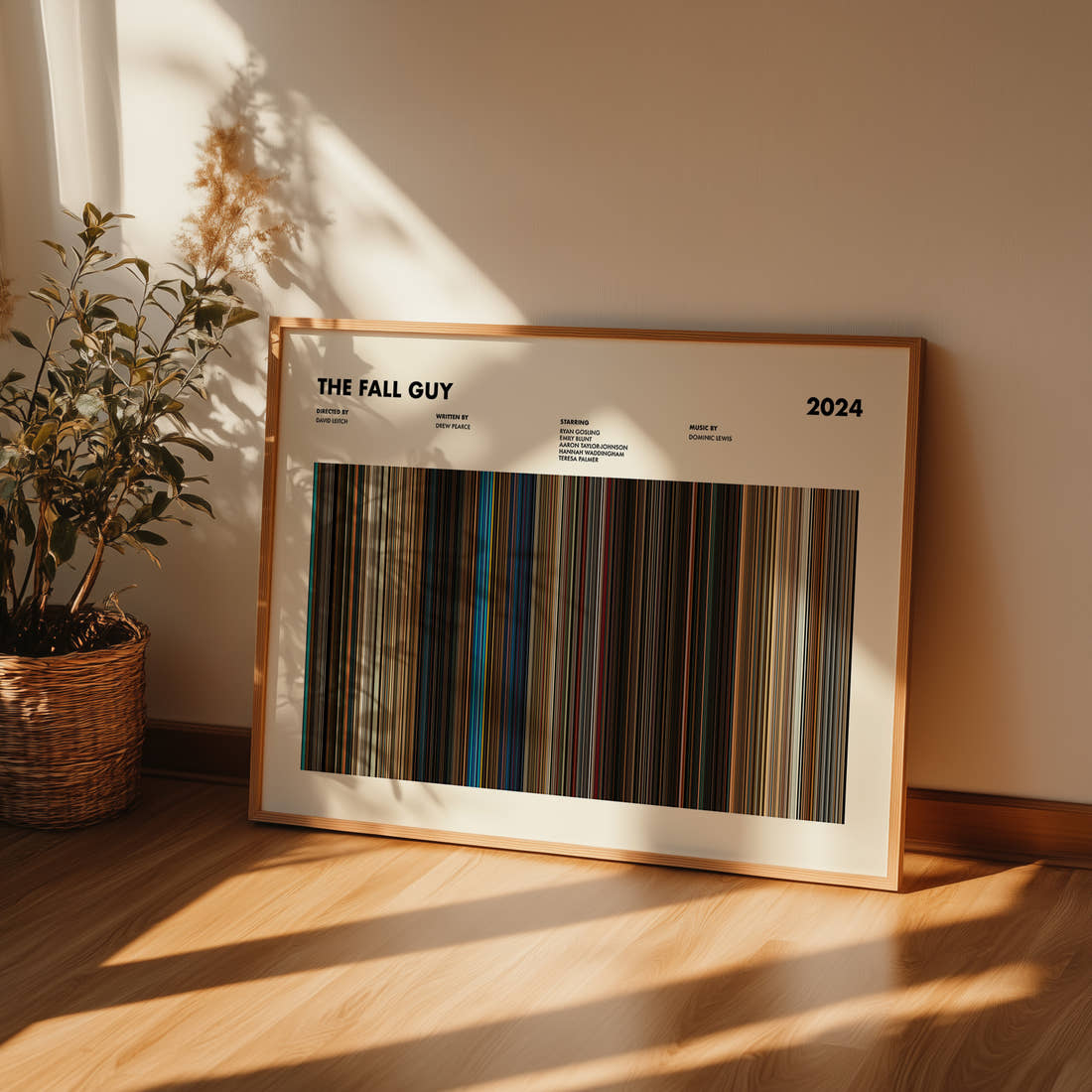 The Fall Guy Movie Barcode Poster framed and leaning against a wall on a wooden floor