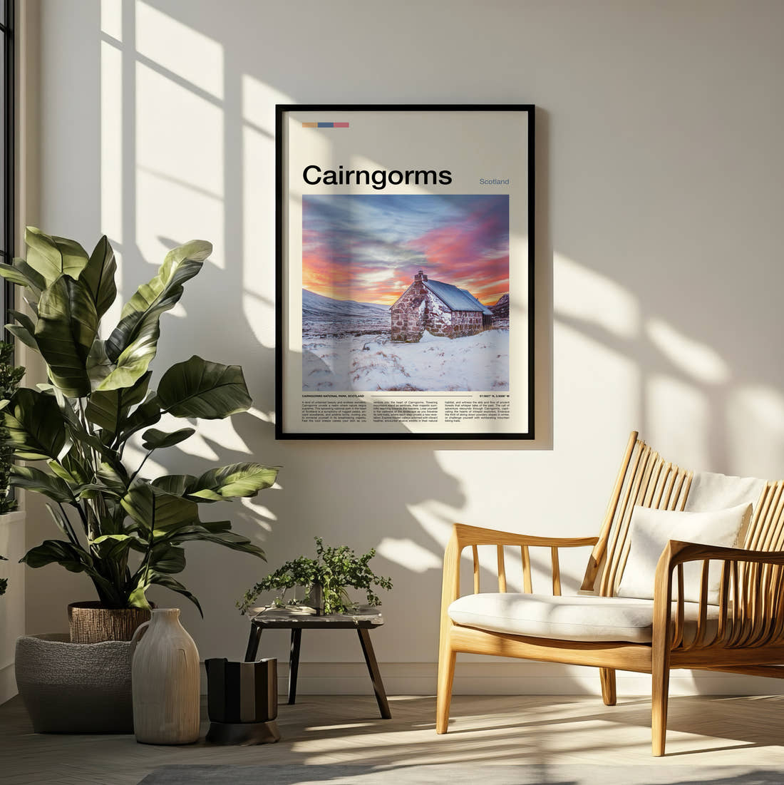 Cairngorms Cottage In The Snow Travel Print framed on a pale wall beside houseplants