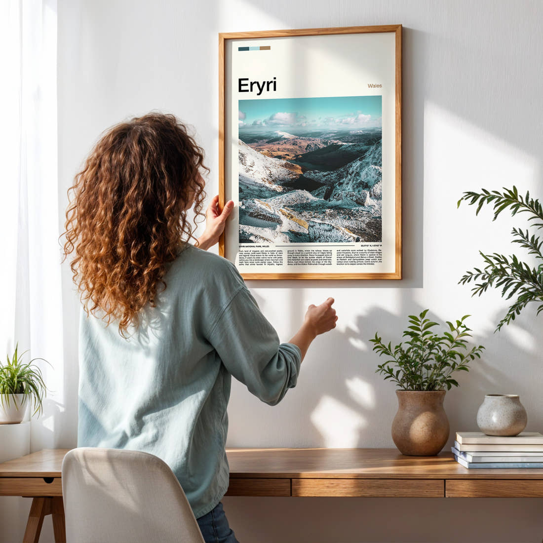 Eryri Snow-Dusted Mountain Valley Travel Print framed on a pale wall beside houseplants