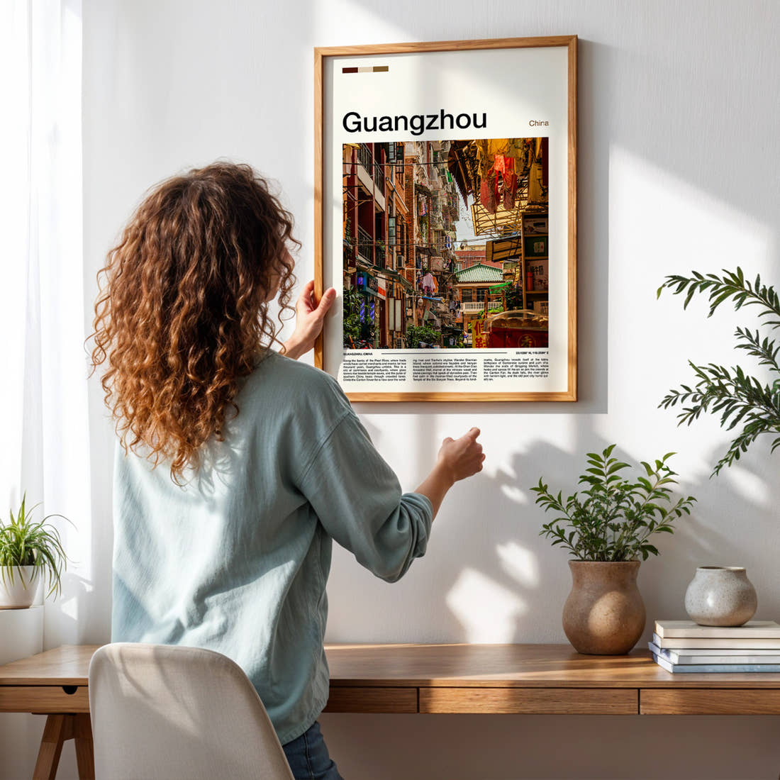 Guangzhou Old Quarter Alleyway Travel Print framed on a pale wall beside houseplants