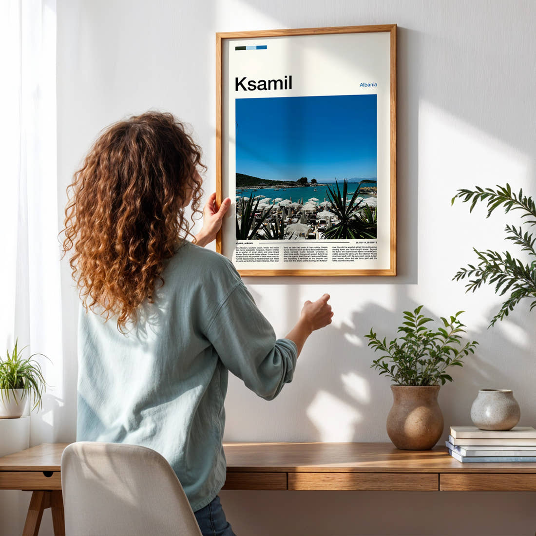 Ksamil Turquoise Beach Umbrellas Travel Print framed on a pale wall beside houseplants