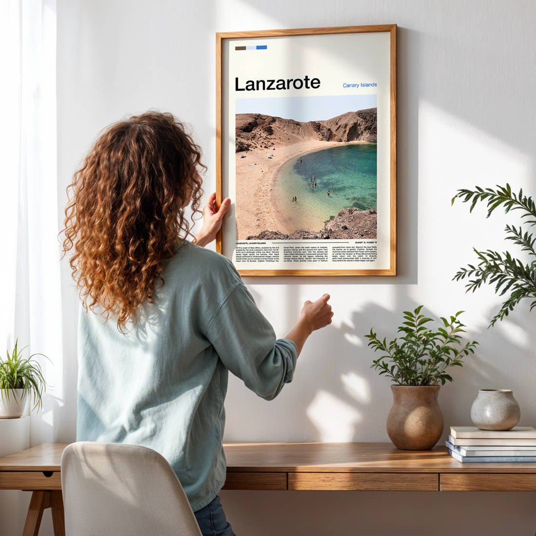 Lanzarote Volcanic Cove Beach Travel Print framed on a pale wall beside houseplants