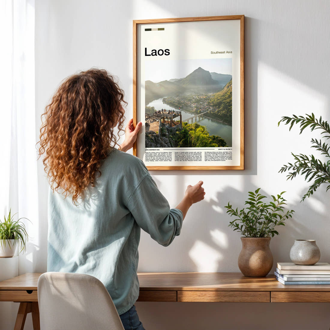 Laos River Valley Viewpoint Travel Print framed on a pale wall beside houseplants