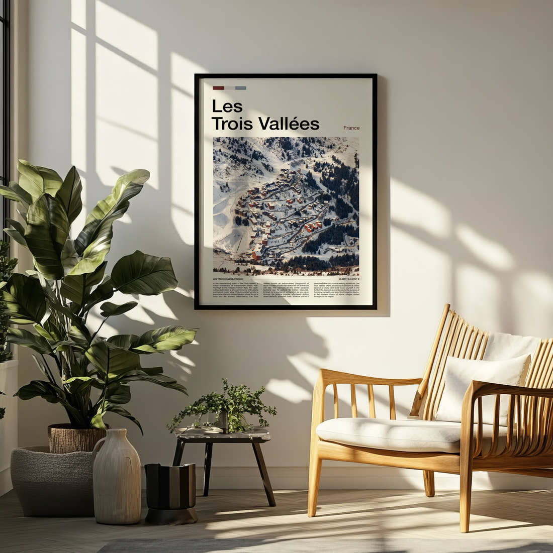 Les Trois Vallees Snowy Ski Village Travel Print framed on a pale wall beside houseplants