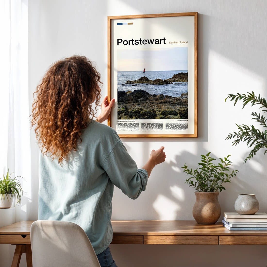 Portstewart Rocky Shoreline Sunset Travel Print framed on a pale wall beside houseplants