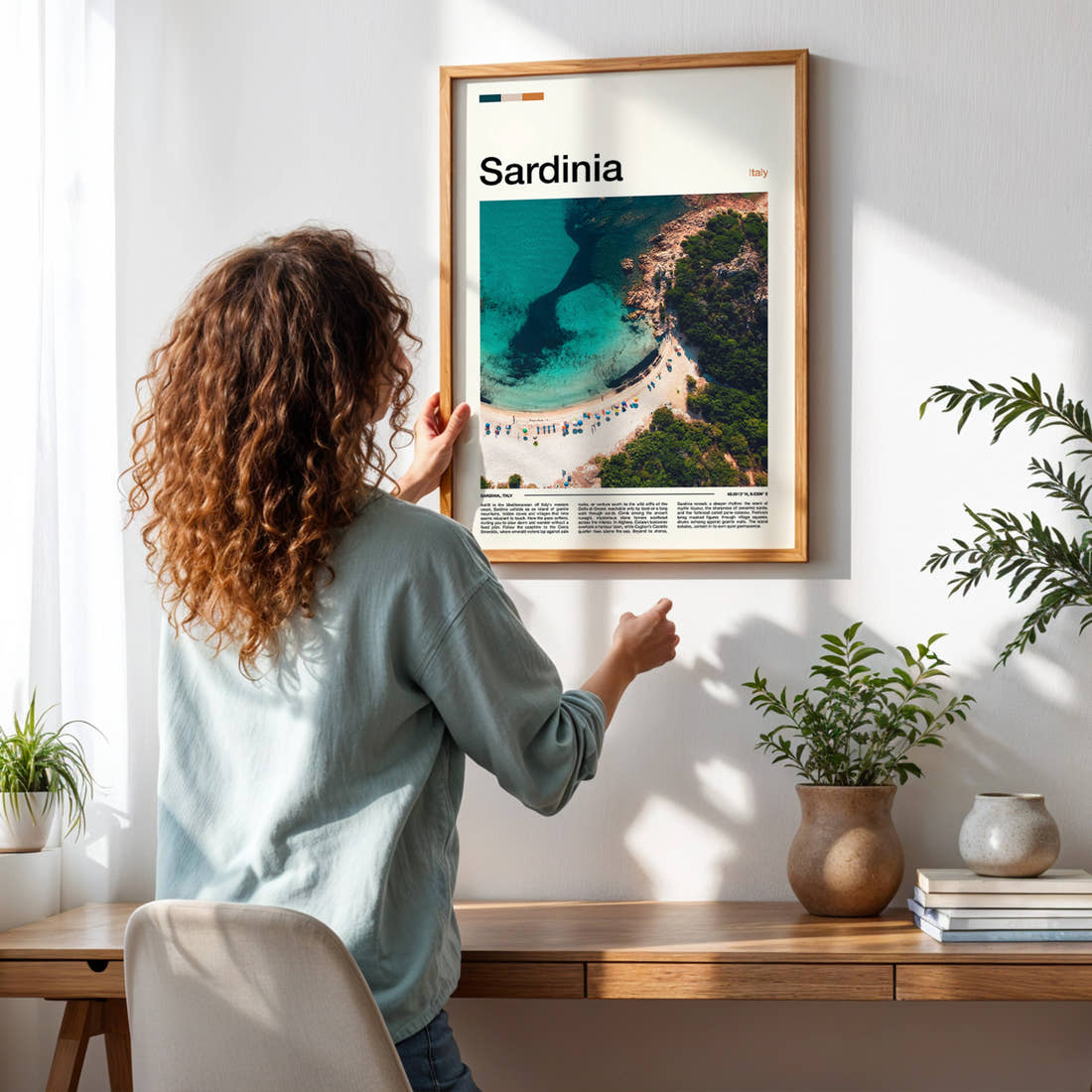 Sardinia Turquoise Cove Aerial Travel Print framed on a pale wall beside houseplants