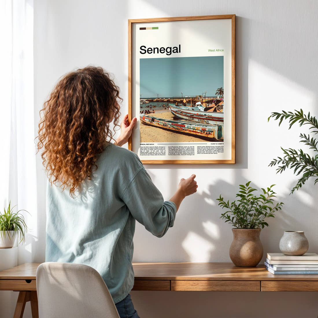 Senegal Weathered Fishing Boats Travel Print framed on a pale wall beside houseplants