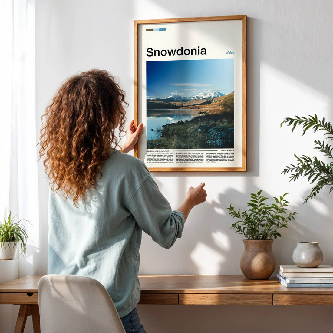 Snowdonia Snow-Capped Mountain Reflection Travel Print framed on a pale wall beside houseplants