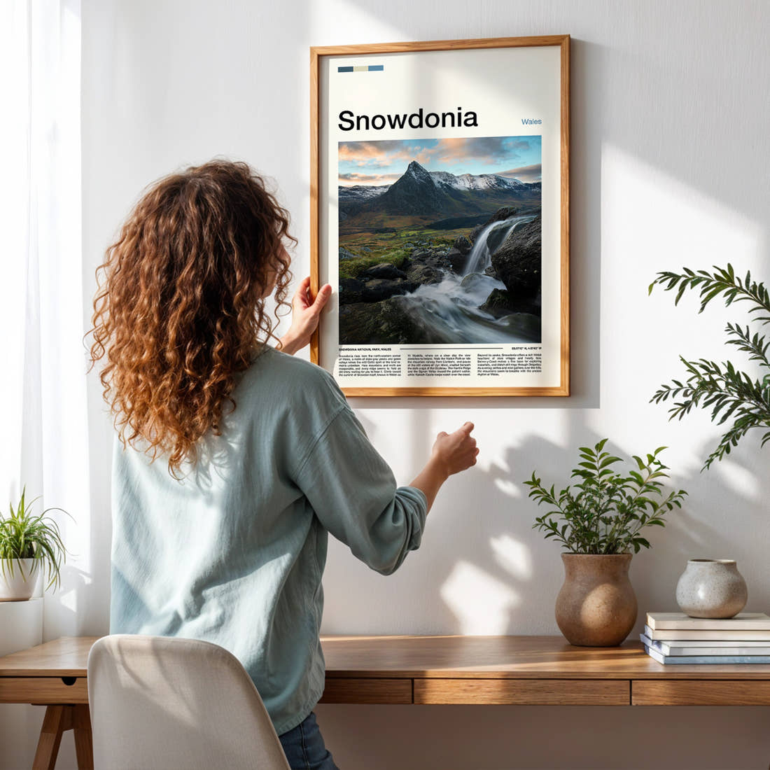 Snowdonia Waterfall And Peaks Travel Print framed on a pale wall beside houseplants