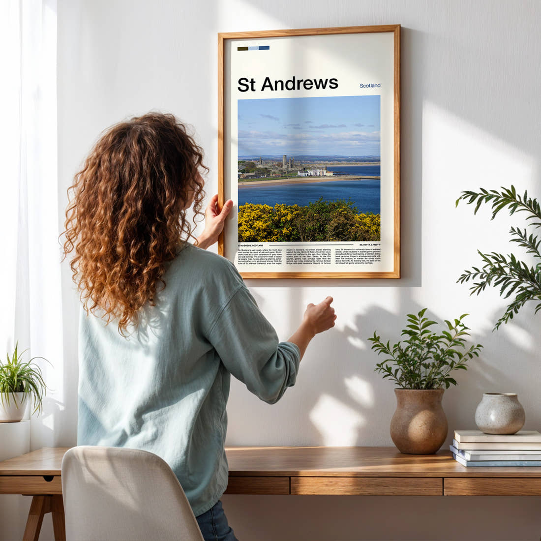 St Andrews Coastal Town View Travel Print framed on a pale wall beside houseplants