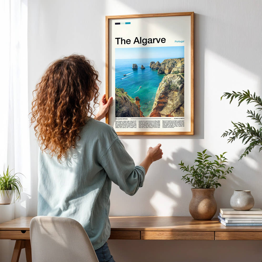 The Algarve Limestone Cliffs And Cove Travel Print framed on a pale wall beside houseplants
