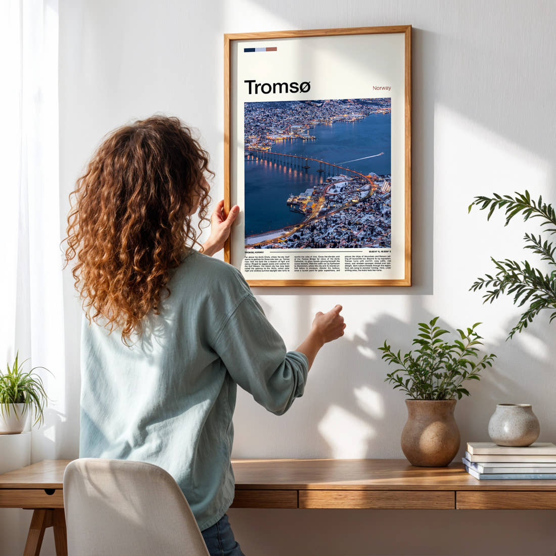 Tromsø Bridge At Dusk Travel Print framed on a pale wall beside houseplants