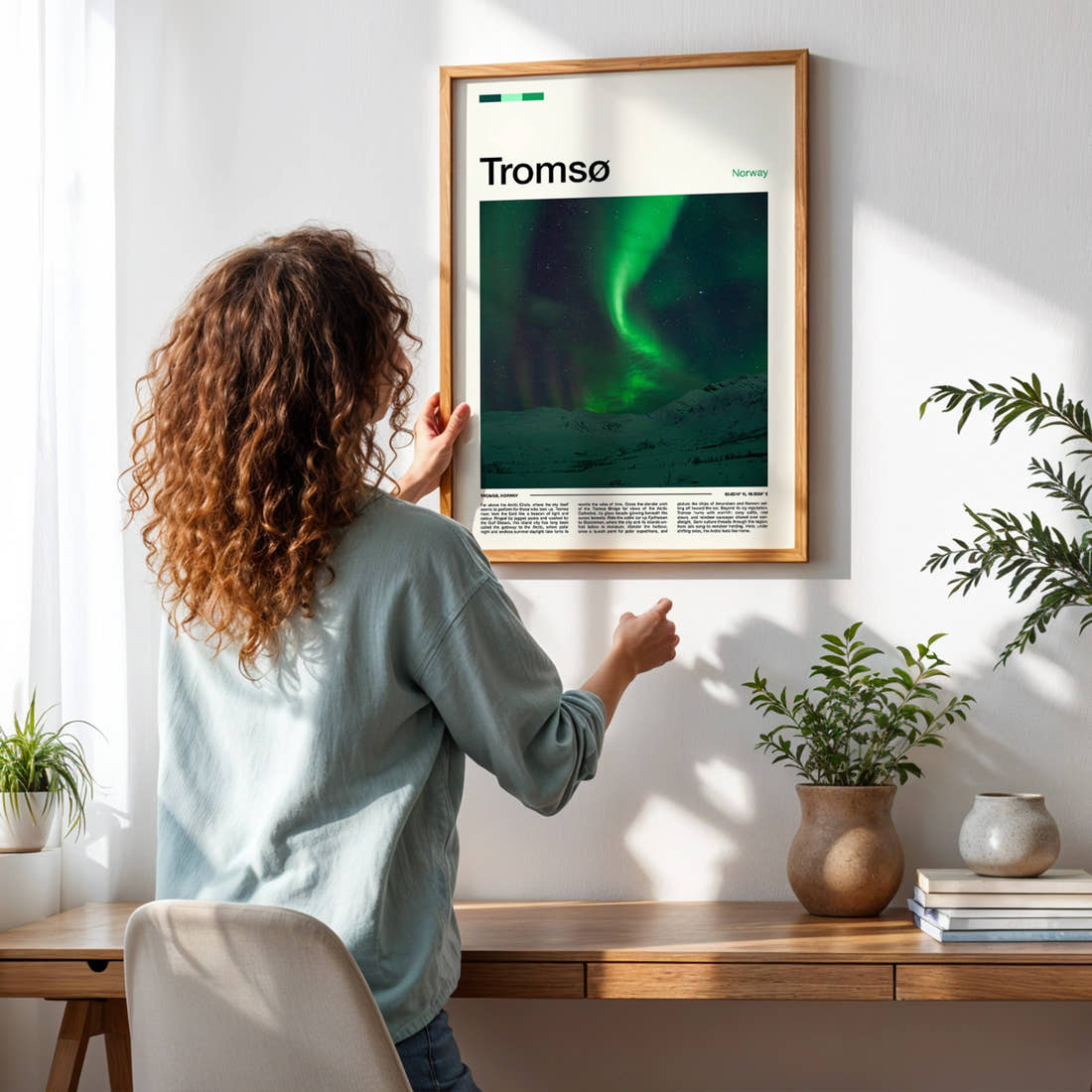 Tromsø Aurora Over Mountains Travel Print framed on a pale wall beside houseplants